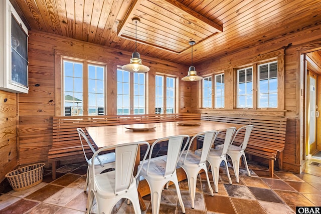 dining room with wooden ceiling, stone tile flooring, and wood walls