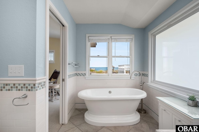 bathroom featuring a wainscoted wall, a soaking tub, tile walls, and tile patterned floors