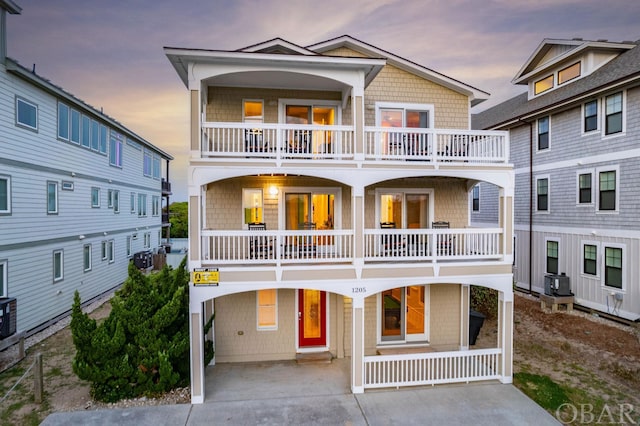 raised beach house with a balcony, driveway, a porch, and a carport