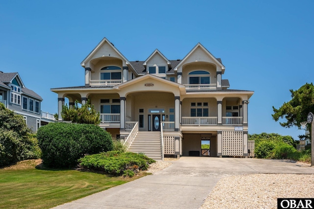 385 Deep Neck Rd Lot # 131, Corolla, NC 27927 - raised beach house featuring a porch, stairs, concrete driveway, a carport, and a balcony