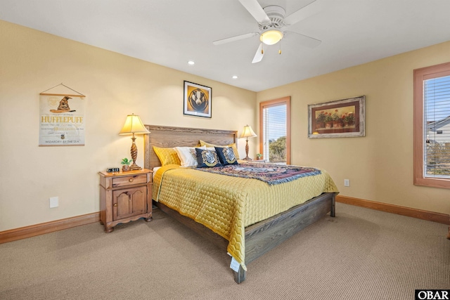 bedroom with ceiling fan, baseboards, light colored carpet, and multiple windows