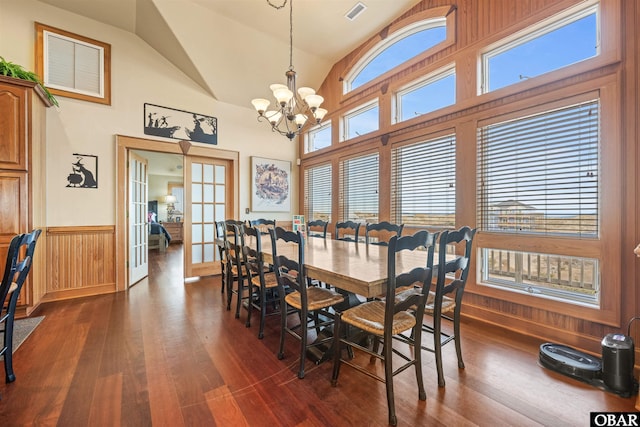 dining space featuring an inviting chandelier, visible vents, wainscoting, high vaulted ceiling, and dark wood-style flooring