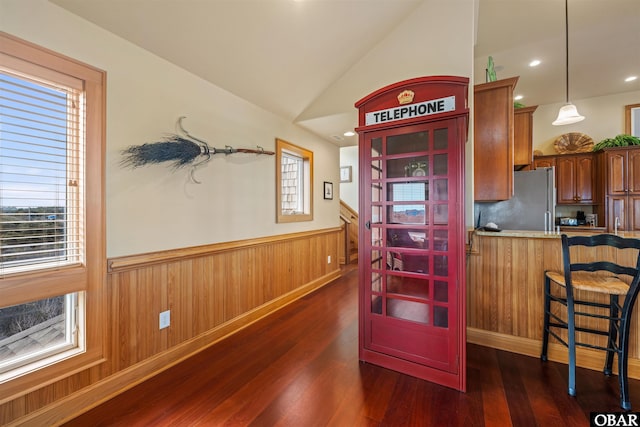kitchen with wainscoting, a breakfast bar area, dark wood-type flooring, and freestanding refrigerator