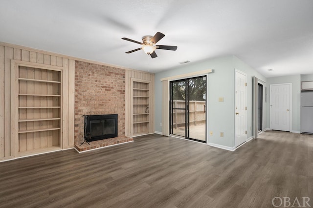 unfurnished living room with built in shelves, a fireplace, dark wood finished floors, and visible vents