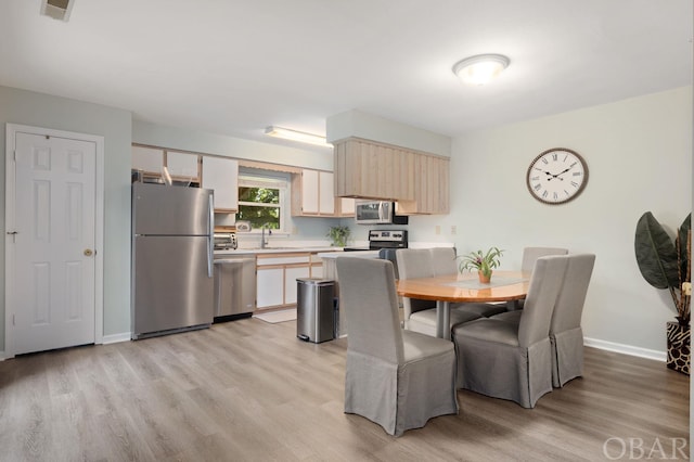 kitchen with a toaster, stainless steel appliances, light countertops, light wood-style floors, and a sink