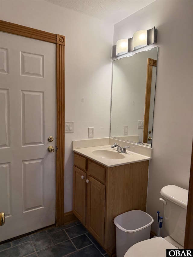 half bath with toilet, a textured ceiling, and vanity