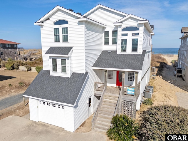 view of front of property featuring a garage, concrete driveway, a shingled roof, and stairway