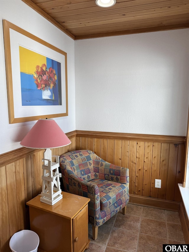 sitting room featuring wooden ceiling, a wainscoted wall, and wooden walls