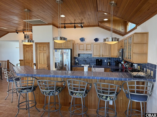 kitchen featuring tasteful backsplash, vaulted ceiling, stainless steel refrigerator with ice dispenser, and tile patterned floors