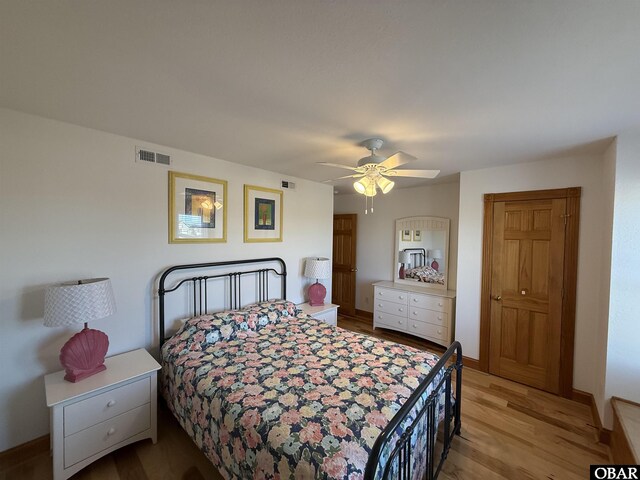 bedroom featuring a ceiling fan, baseboards, visible vents, and wood finished floors