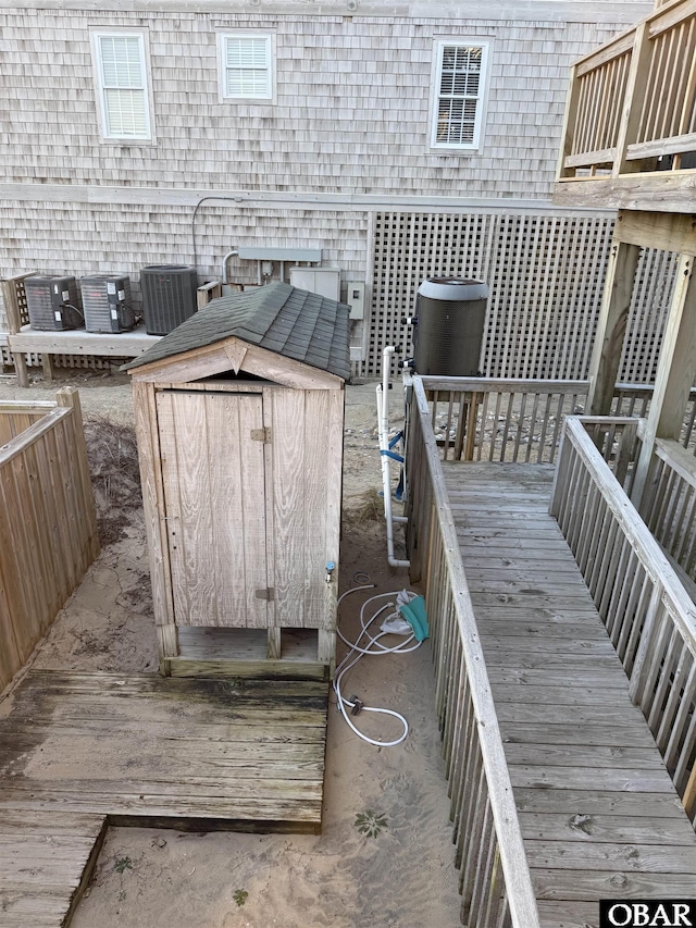 deck featuring a shed, central AC unit, and an outbuilding