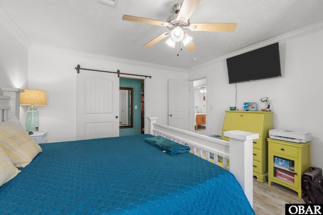 bedroom featuring a barn door, wood finished floors, a ceiling fan, and ornamental molding