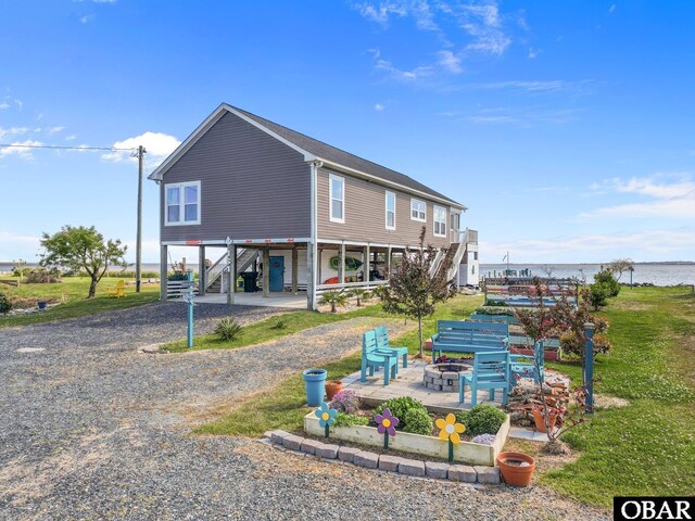 back of property with stairway, gravel driveway, an outdoor fire pit, and a carport