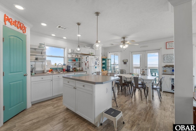 kitchen with a center island, a ceiling fan, open shelves, white cabinets, and freestanding refrigerator