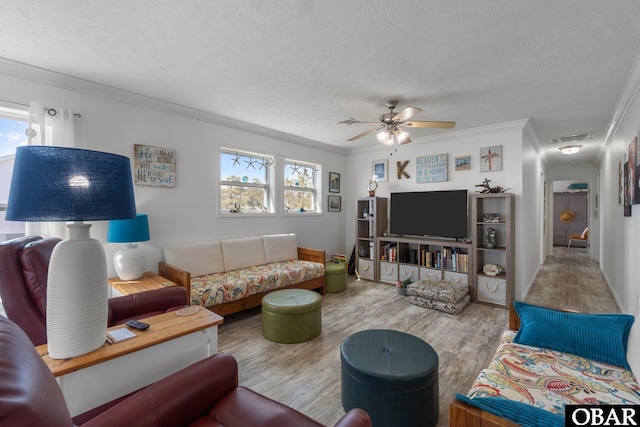 living room featuring wood finished floors, a textured ceiling, crown molding, and a ceiling fan