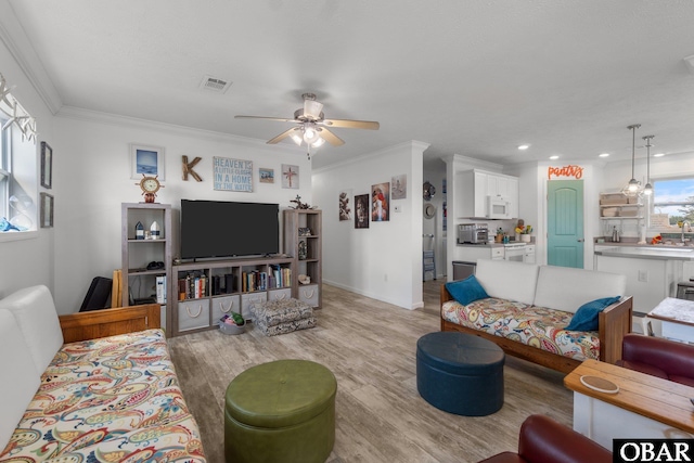 living area with visible vents, recessed lighting, light wood-style floors, a ceiling fan, and crown molding
