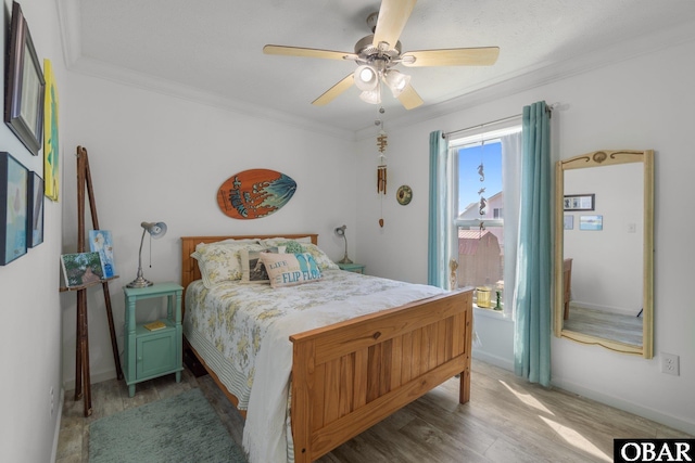 bedroom with baseboards, a ceiling fan, wood finished floors, and ornamental molding