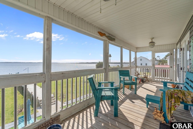 sunroom / solarium featuring a ceiling fan and a water view