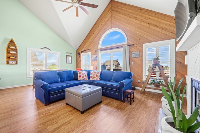 living area with light wood-style floors, a healthy amount of sunlight, and wood walls