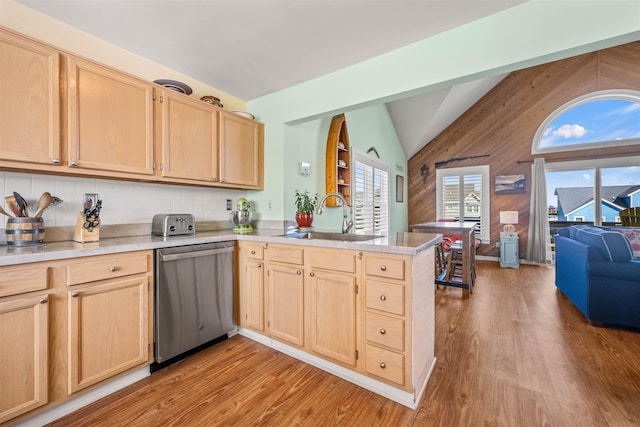 kitchen featuring a sink, a peninsula, dishwasher, and light brown cabinetry