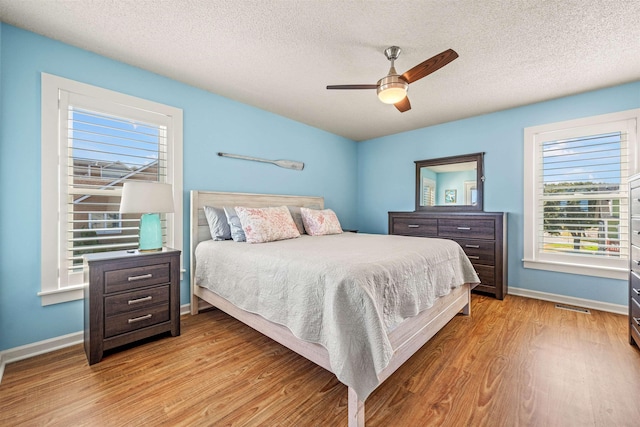 bedroom featuring visible vents, ceiling fan, a textured ceiling, wood finished floors, and baseboards