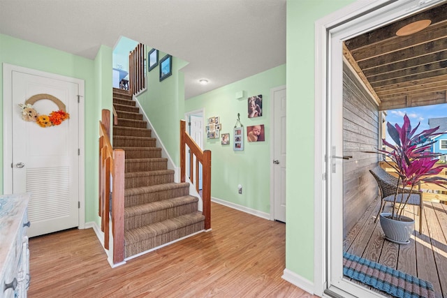 foyer with baseboards, stairway, and light wood-style floors