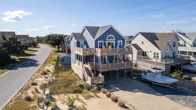 back of house featuring a carport, concrete driveway, and a balcony