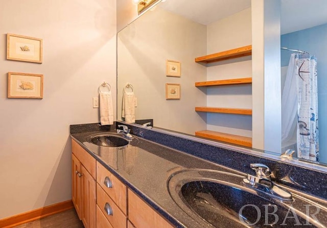 bathroom with double vanity, baseboards, a sink, and wood finished floors