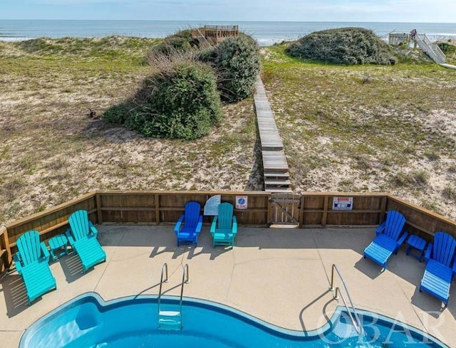 view of swimming pool with a water view, a patio area, and a gate