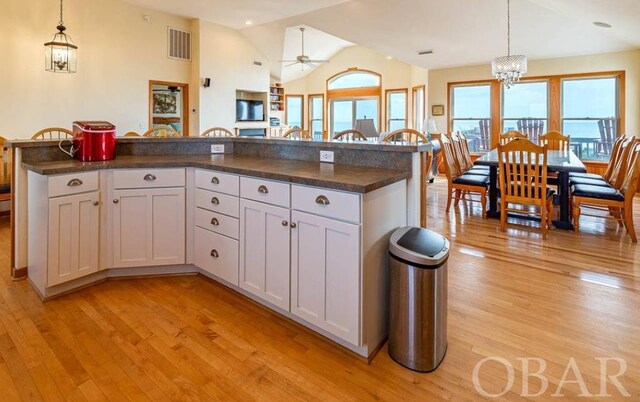 kitchen with dark countertops, a center island, white cabinetry, and pendant lighting