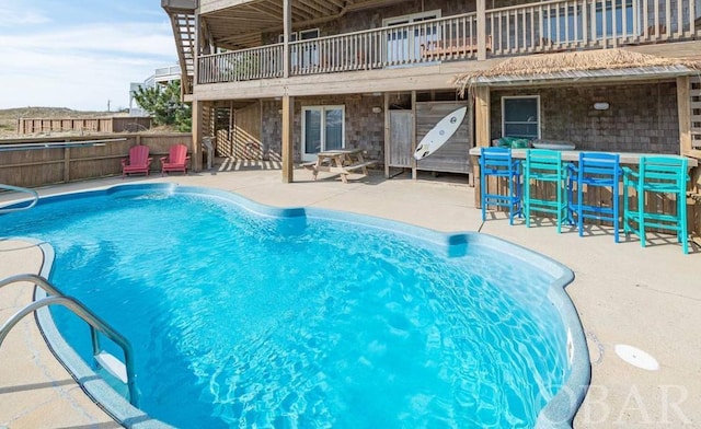 view of swimming pool with a patio area, fence, a hot tub, and exterior bar