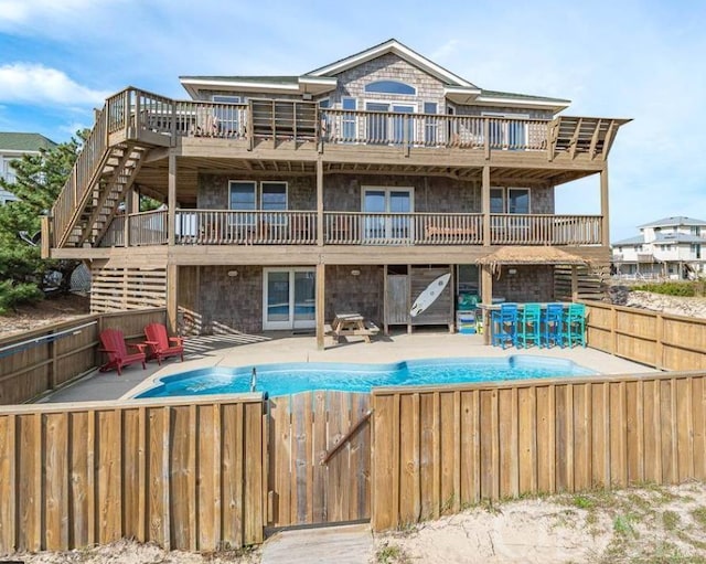 back of property featuring a patio, an outdoor pool, stairway, and fence