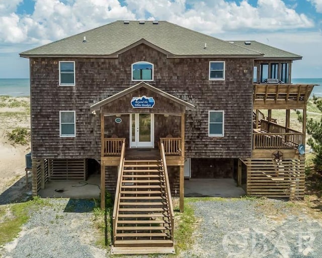 view of front of home featuring a shingled roof, cooling unit, gravel driveway, and a water view