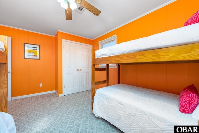 bedroom featuring a closet, light colored carpet, visible vents, ornamental molding, and ceiling fan