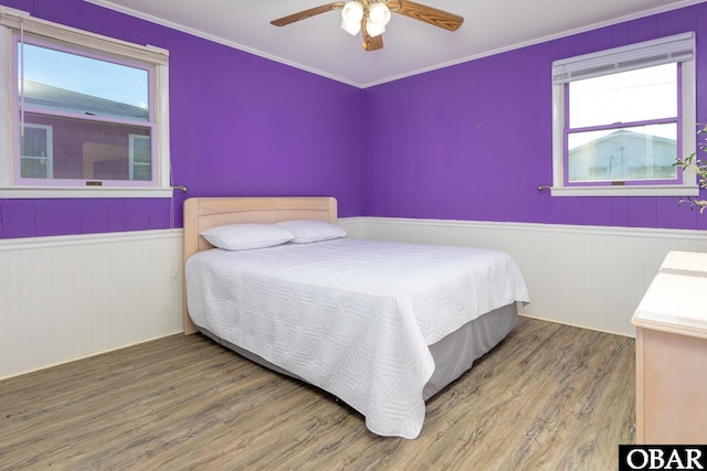 bedroom featuring multiple windows, wainscoting, and wood finished floors