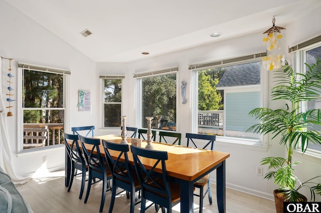 dining area with light wood-style floors, lofted ceiling, and visible vents