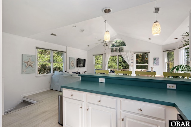 kitchen featuring dark countertops, open floor plan, white cabinets, and decorative light fixtures