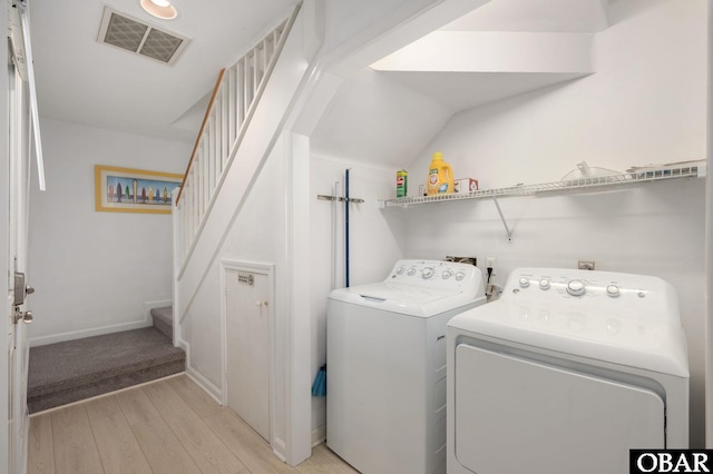 washroom featuring light wood finished floors, laundry area, baseboards, visible vents, and washer and clothes dryer