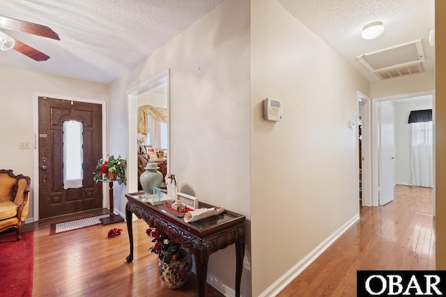 entrance foyer with wood-type flooring, ceiling fan, a textured ceiling, and baseboards