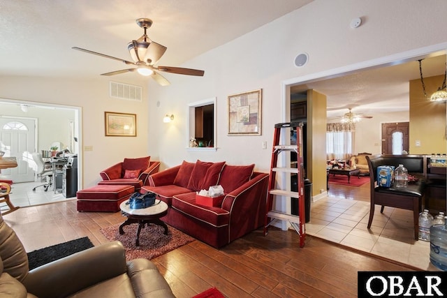 living room with vaulted ceiling, wood-type flooring, visible vents, and ceiling fan