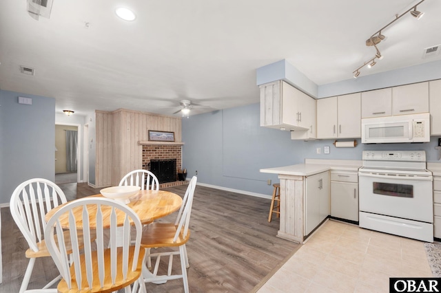 kitchen with white appliances, visible vents, a ceiling fan, light countertops, and a fireplace