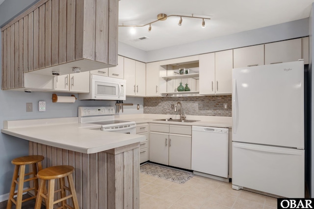 kitchen featuring a peninsula, white appliances, a sink, open shelves, and a kitchen bar