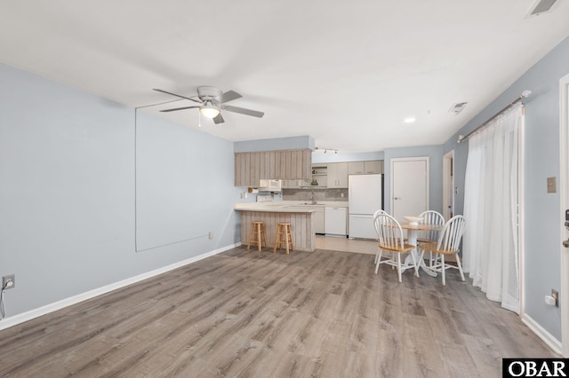 kitchen with white appliances, visible vents, a peninsula, light countertops, and light wood-type flooring