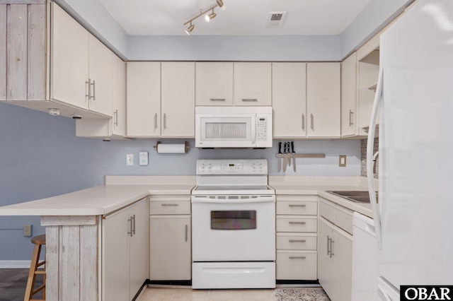 kitchen featuring white appliances, a breakfast bar, visible vents, white cabinets, and light countertops