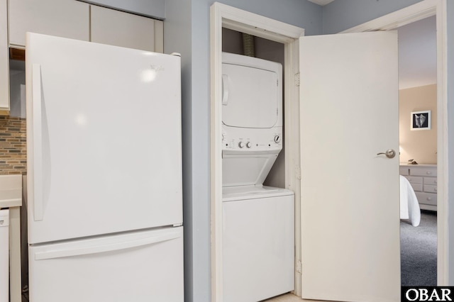 laundry room featuring light carpet, laundry area, and stacked washer / drying machine