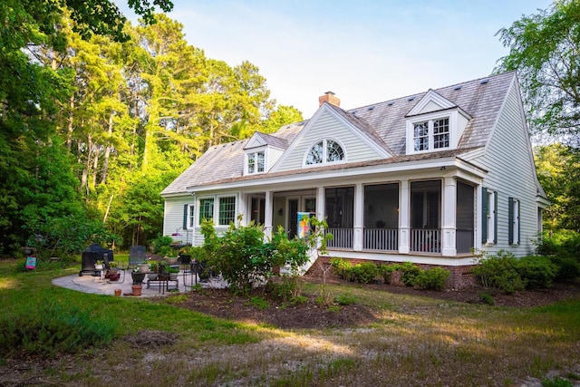 rear view of house featuring a patio area, a chimney, and a yard