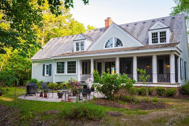 back of house with a patio area, a lawn, and a chimney