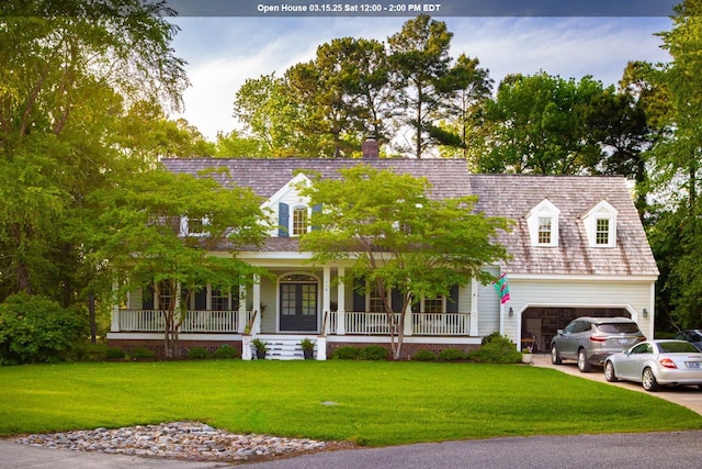 cape cod home featuring an attached garage, a front yard, covered porch, french doors, and driveway