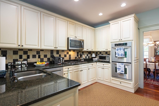 kitchen featuring a toaster, a sink, stainless steel appliances, a notable chandelier, and tasteful backsplash