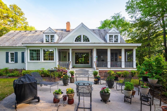 back of house featuring a chimney, a patio, and a sunroom